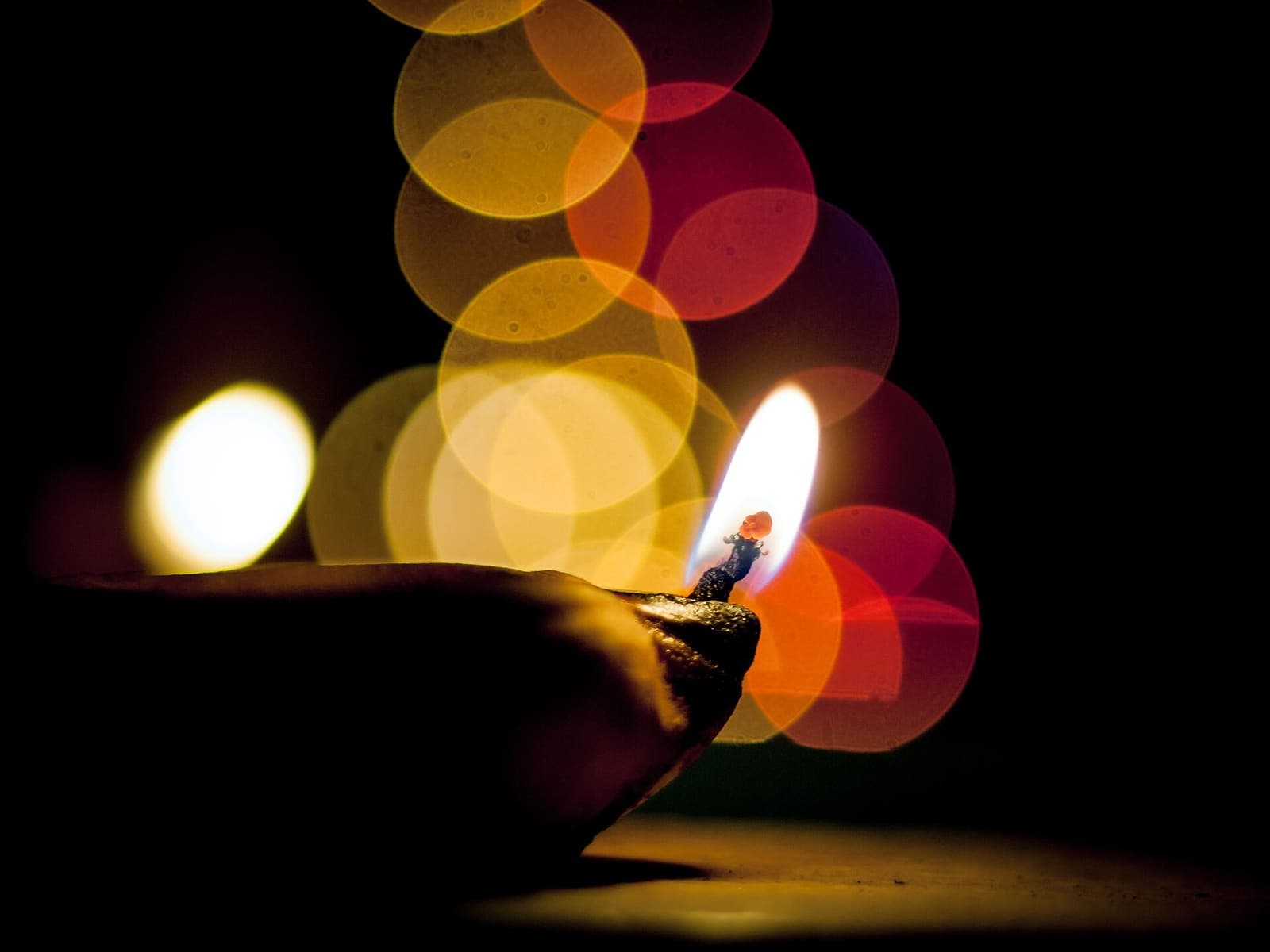 A single clay diya with a bright flame
